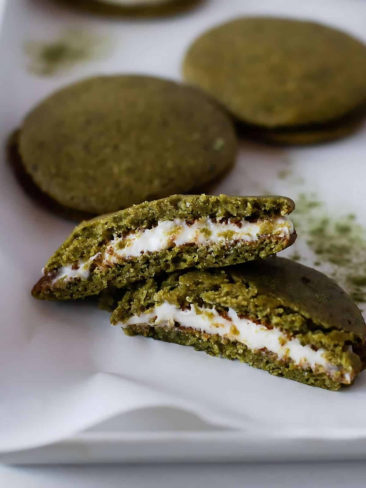 A sliced matcha whoopie pie next to whole matcha whoopie pies.