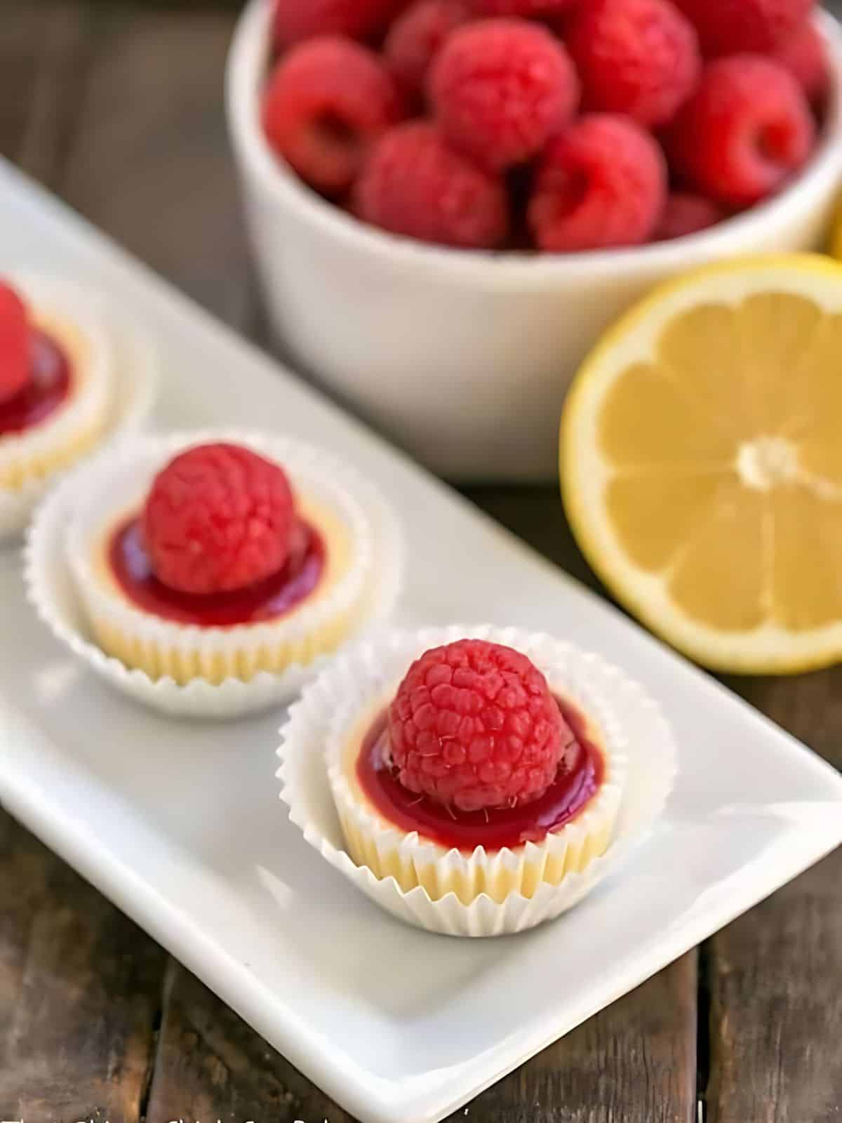 Mini cheesecakes with raspberries on top and raspberry filling.