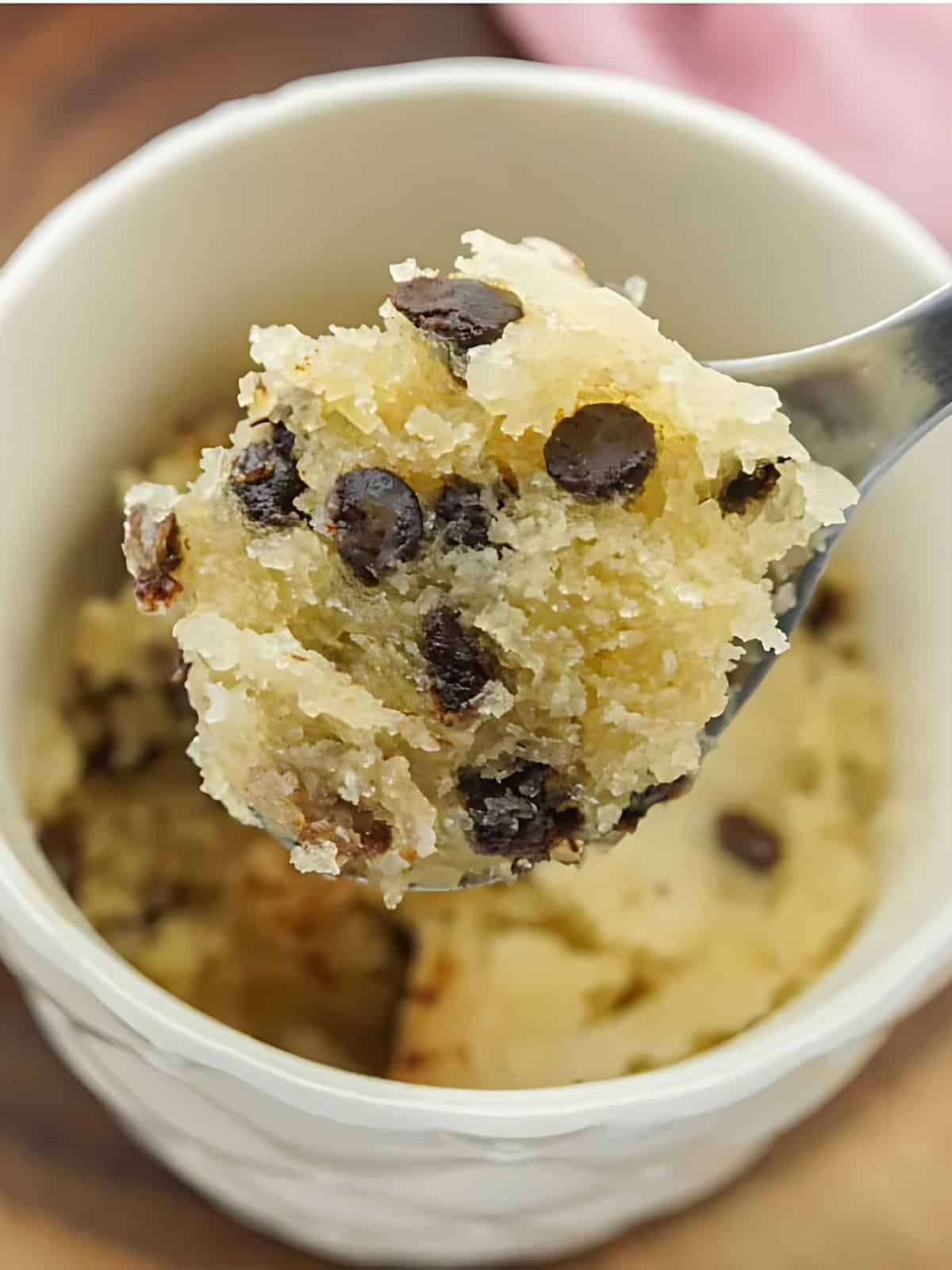 A serving of chocolate chip mug cake on a spoon topped with bits of chocolate chips.