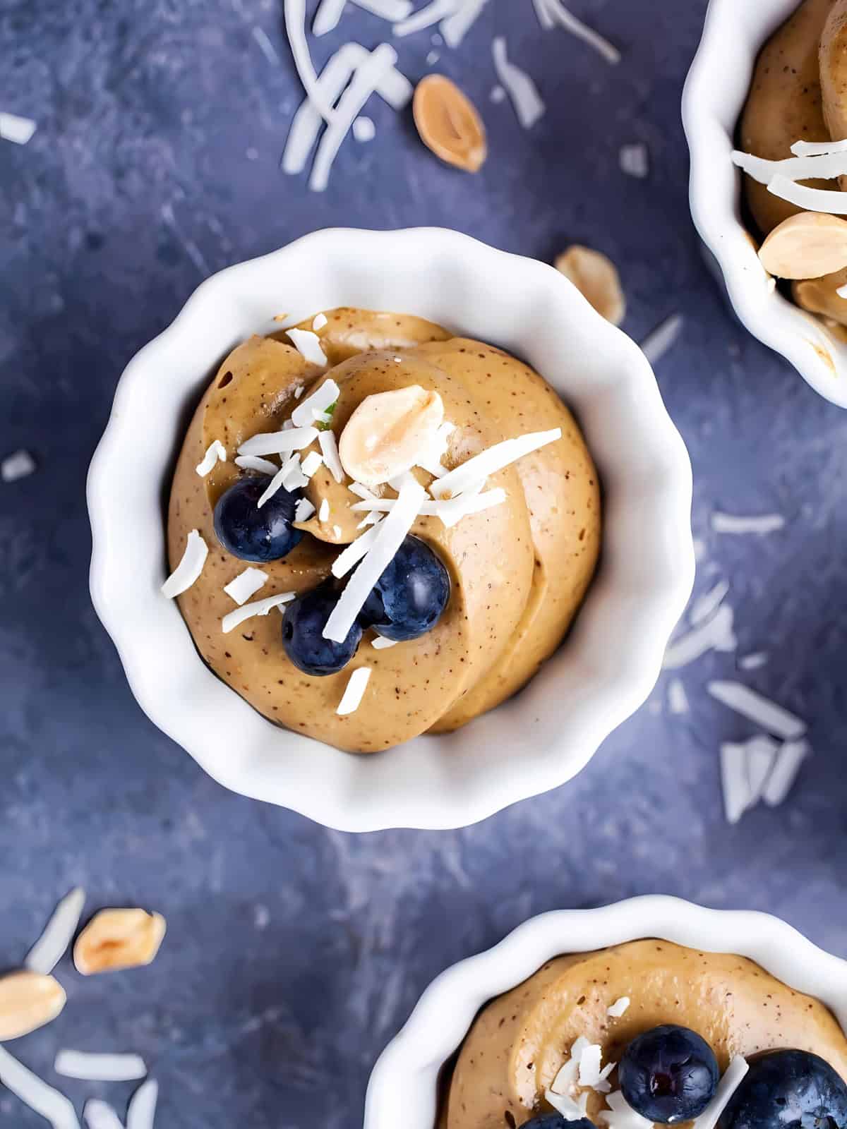 Chocolate peanut butter mousse placed in a small bowl topped with nuts and blueberries.