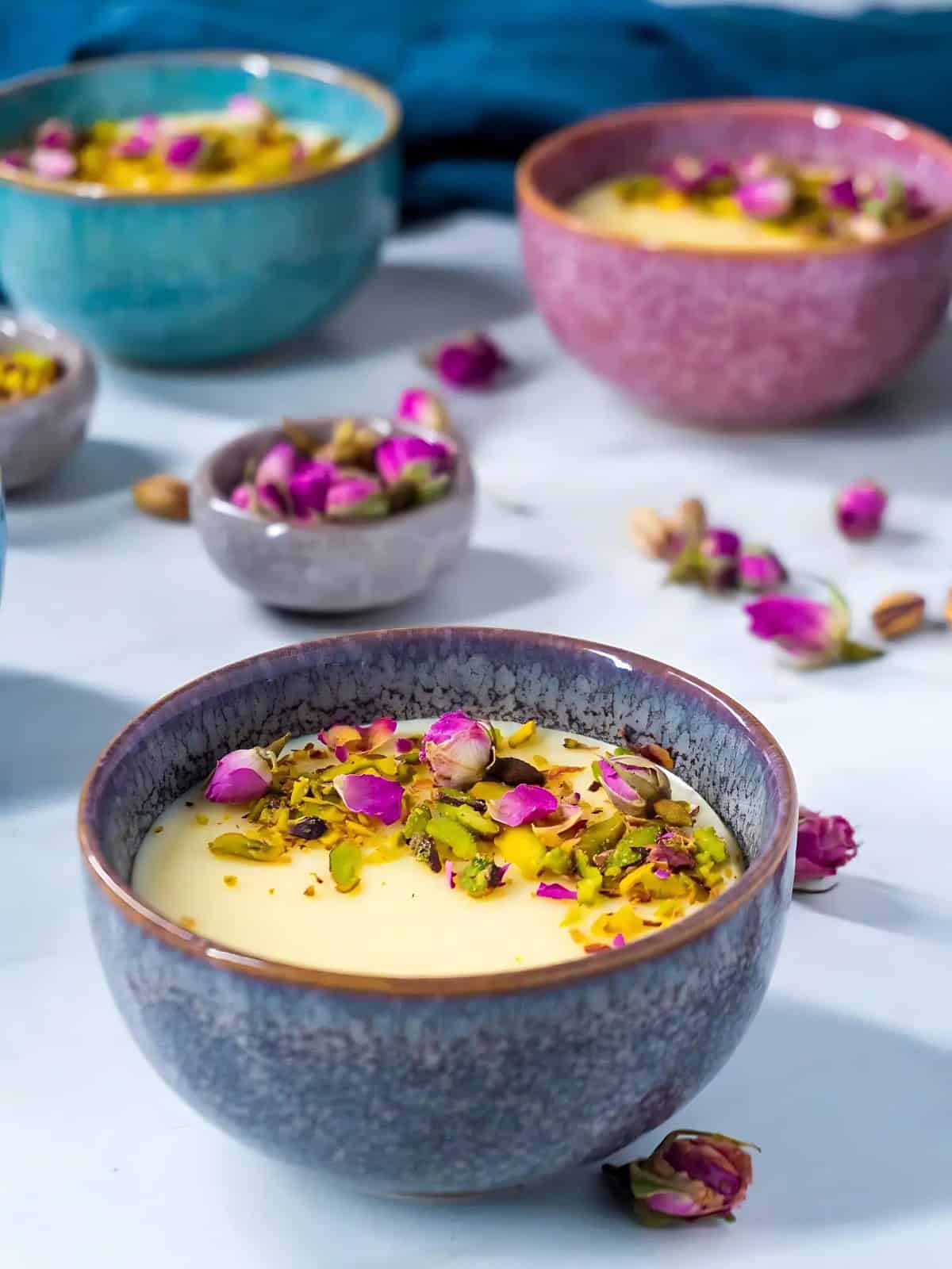 Milk pudding in a porcelain glass bowl topped with fresh flower petals.