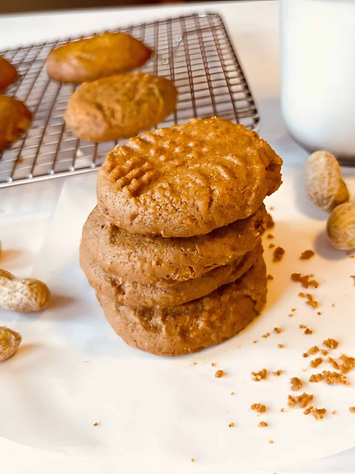 Stacked peanut butter cookies next to whole peanuts.