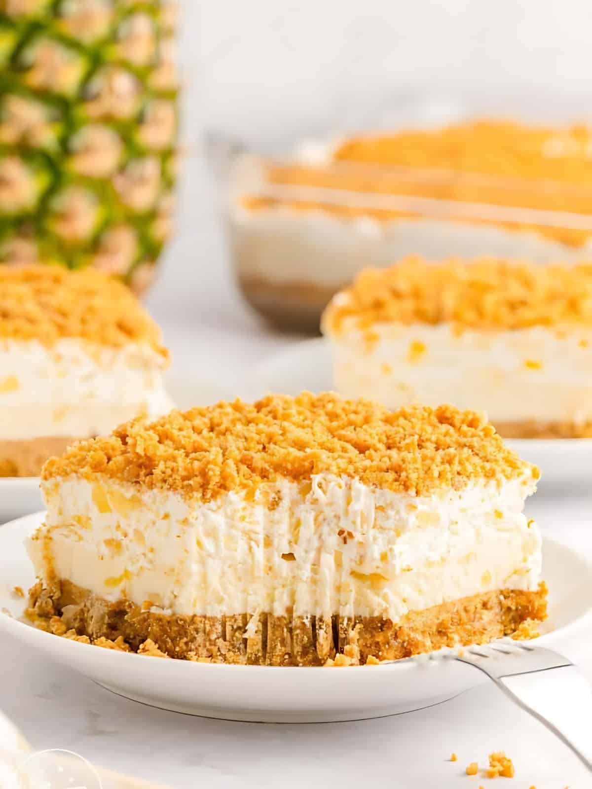A slice of pineapple dream dessert topped with crunch graham bits on a plate.