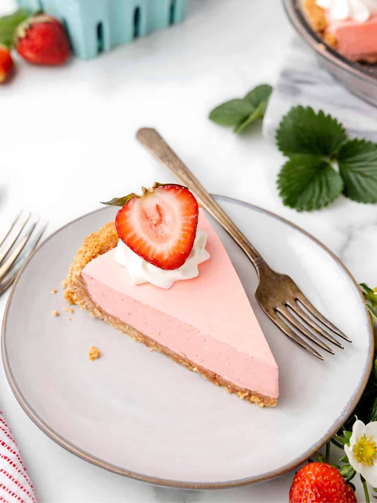 A slice of strawberry jello pie topped with sliced fresh strawberry.