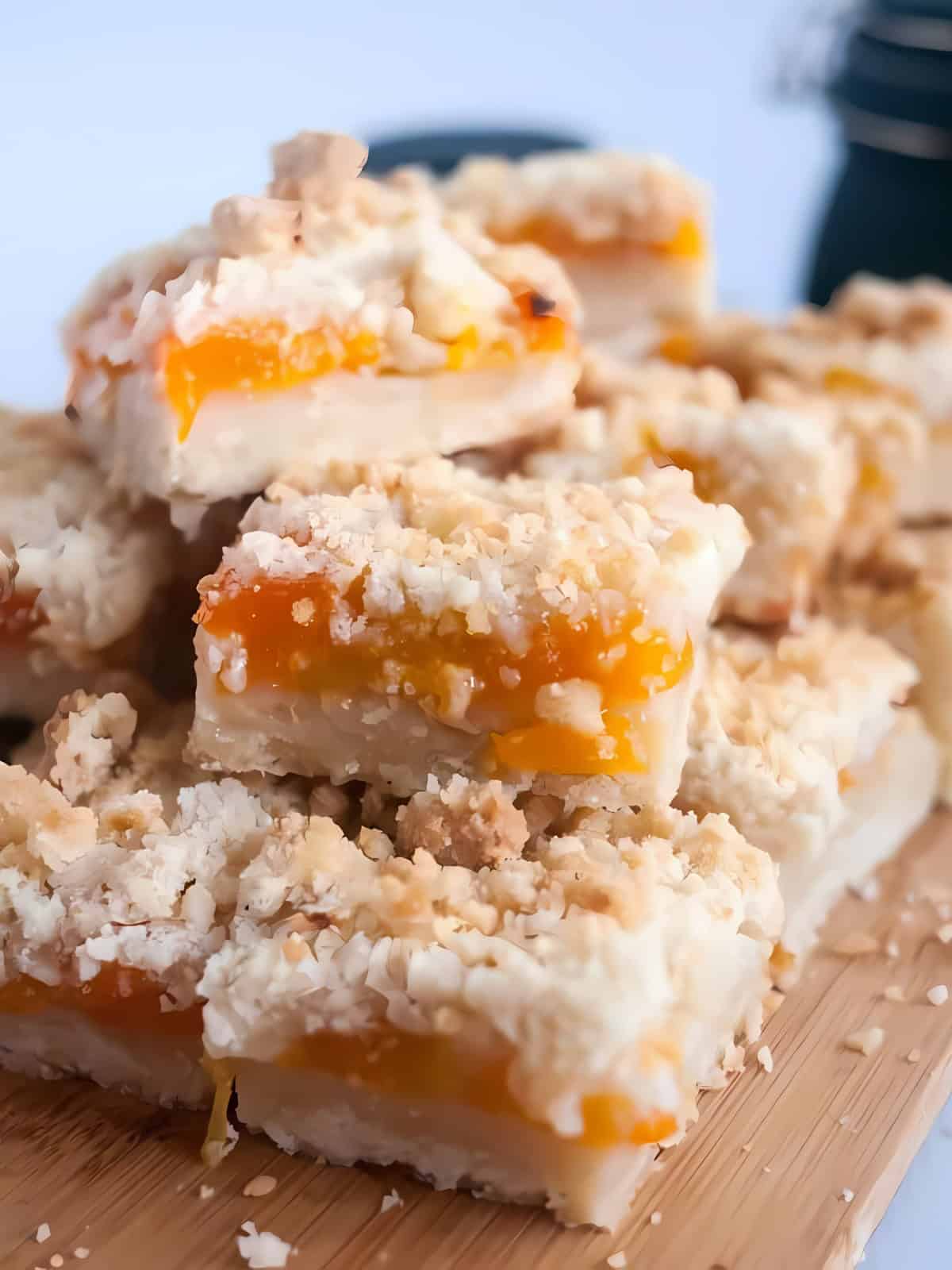 Square cuts of apricot crumble bars on a wooden board.