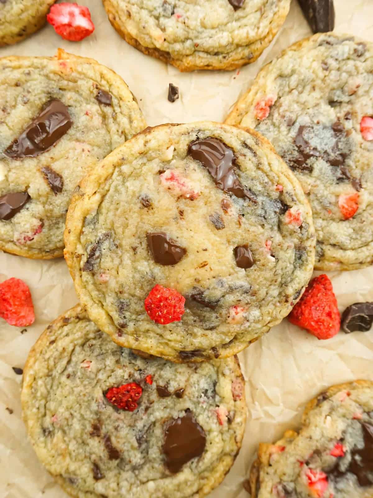 A batch of chocolate chunk strawberry cookies topped with slices of strawberries.