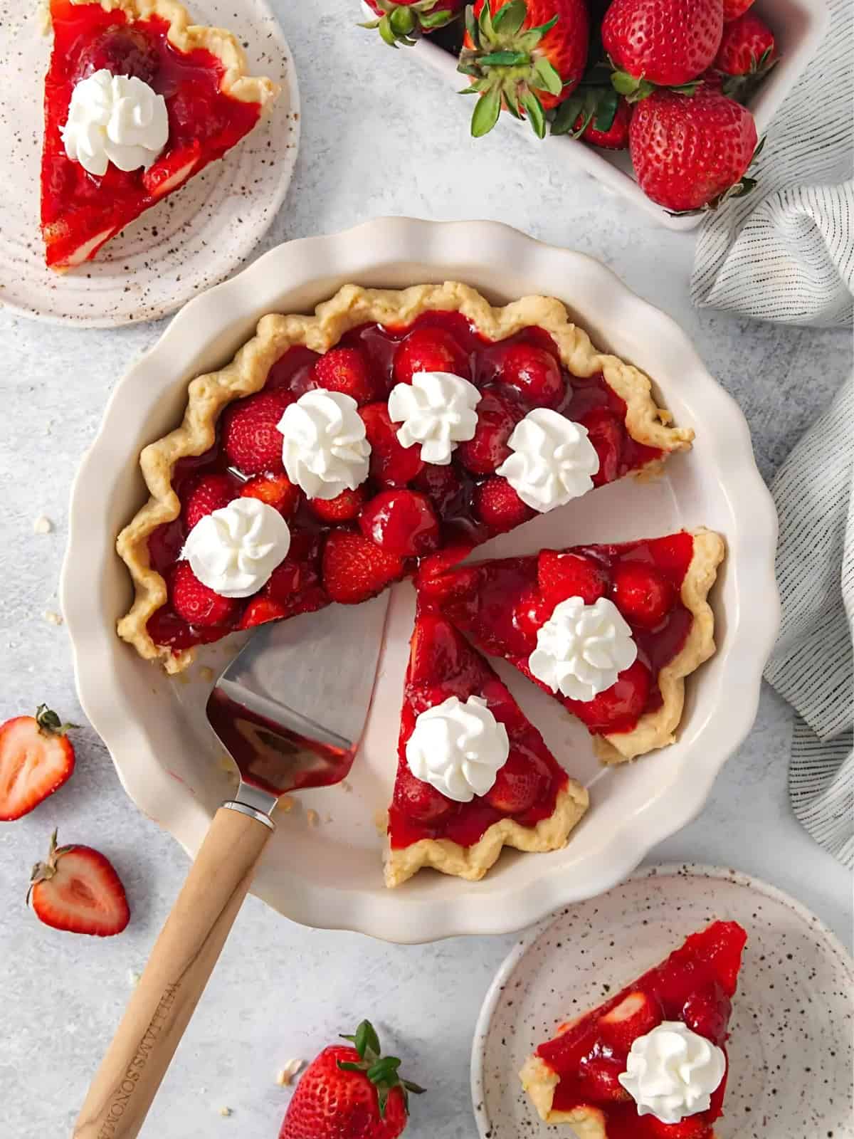 Fresh strawberry pie topped with sliced strawberries and whipped cream.