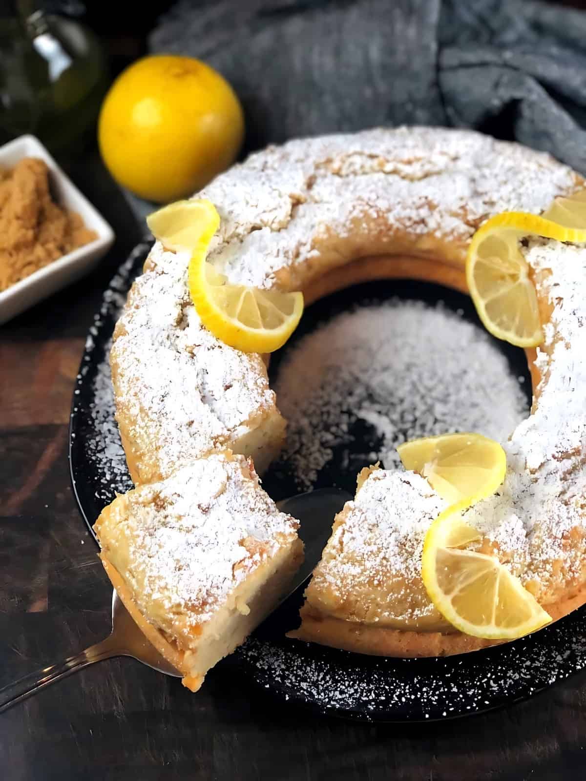 Italian Lemon Ricotta Cake sprinkled with powdered sugar topped with lemon slices.