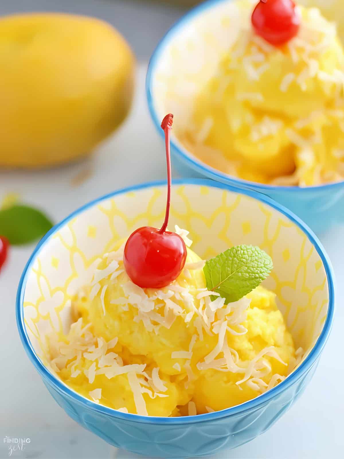 Servings of Mango Pineapple Sorbet with fresh cherry and herb on top.