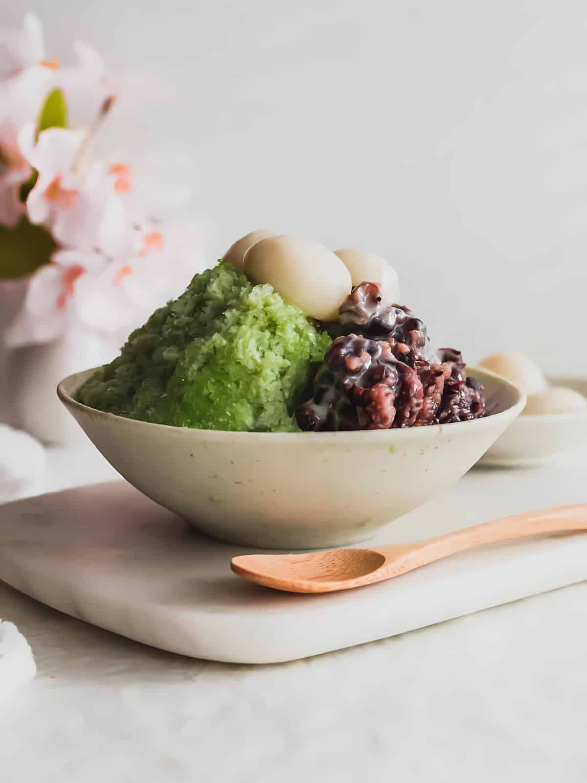 A bowl of Matcha Bingsu and sweet red bean topped with mochi.
