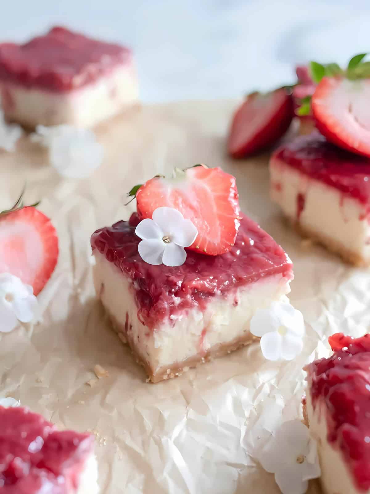 Cube size cutlets of Strawberry Cheesecake Bars with sliced strawberry on top.
