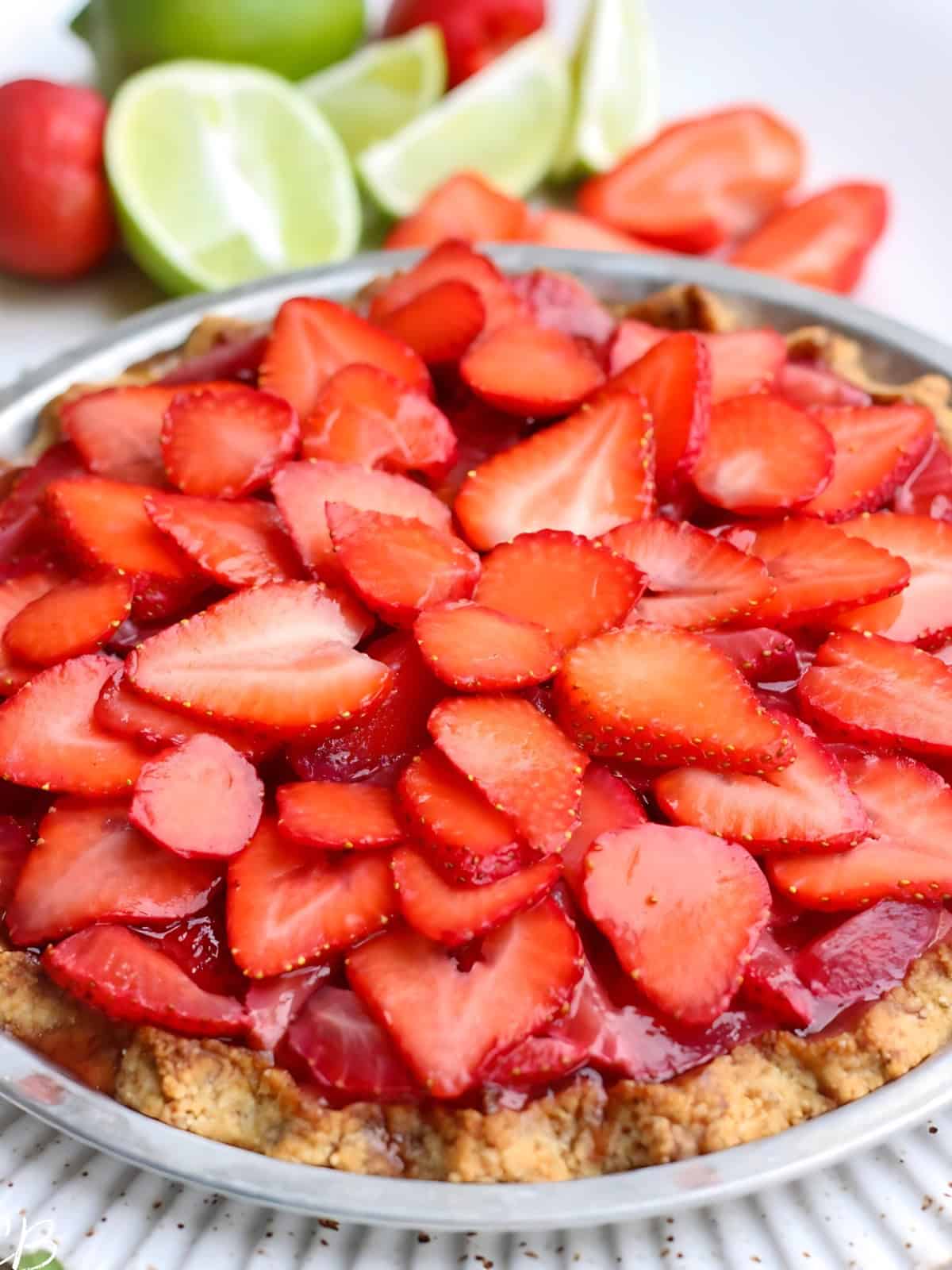 Strawberry Coconut Lime Cream Pie on a pie tray, topped with thinly sliced strawberries arranged in a flower design.