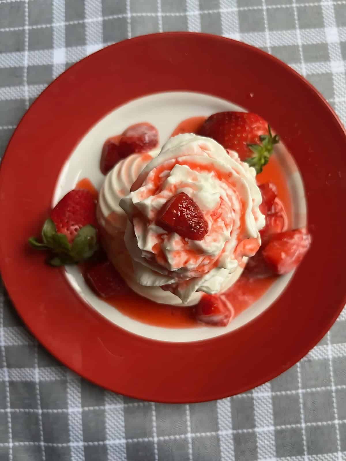 Strawberry Meringue Sundae topped with fresh sliced strawberries on a red plate.