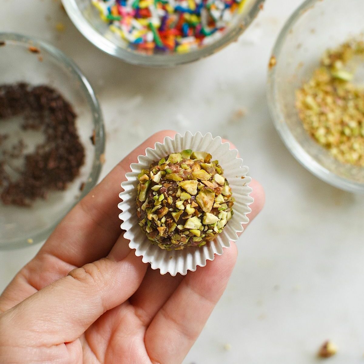 brigadeiro ball, coated with chopped nuts, in a mini cupcake liners.