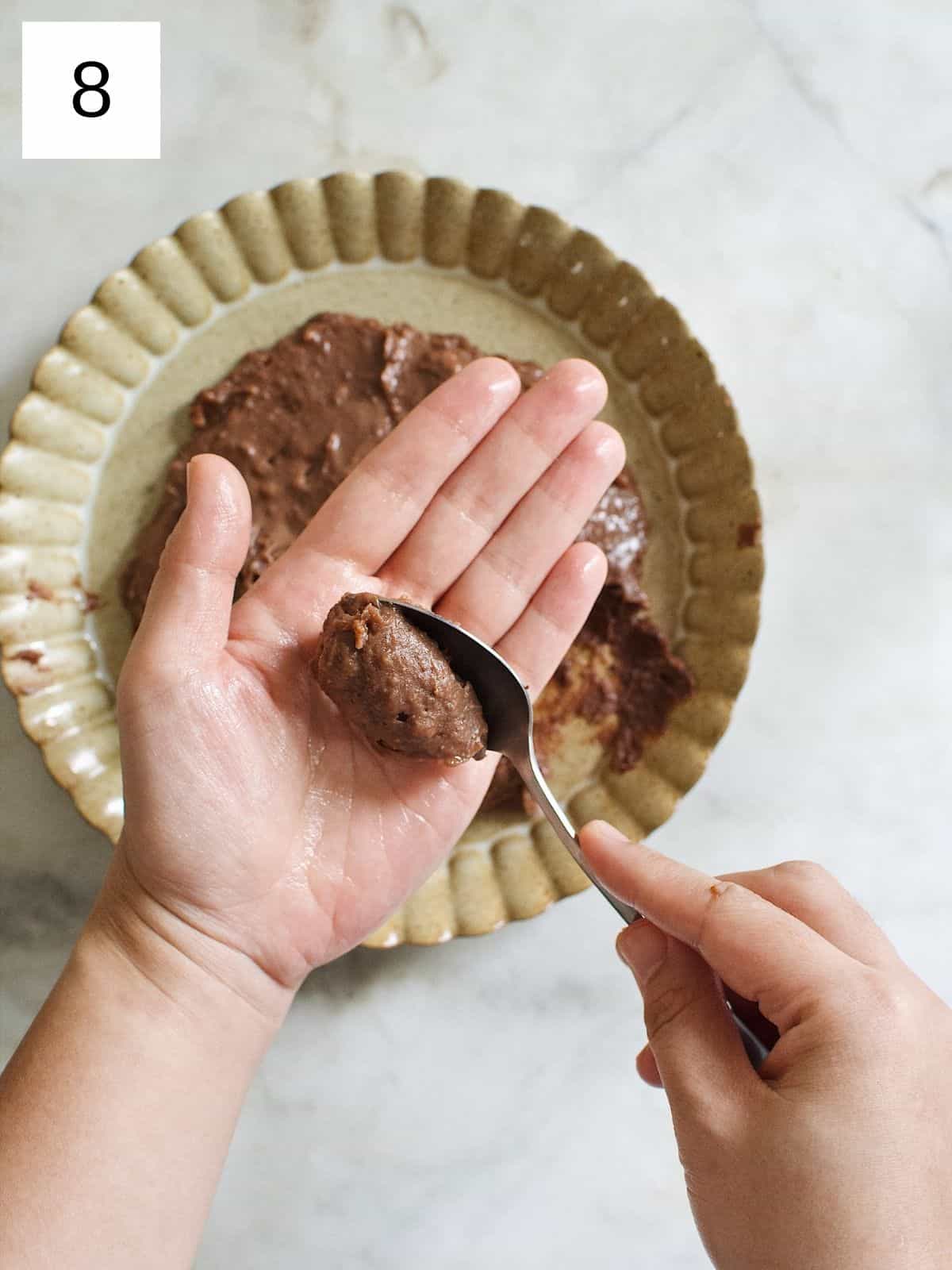scooped portion of brigadeiro on greased hands.