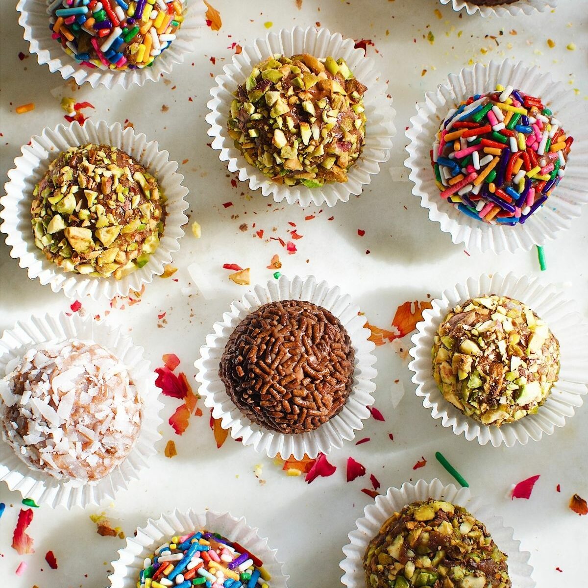 brigadeiro balls, coated with chocolate sprinkles, chopped nuts, assorted sprinkles, and coconut flakes, in a mini cupcake liners.