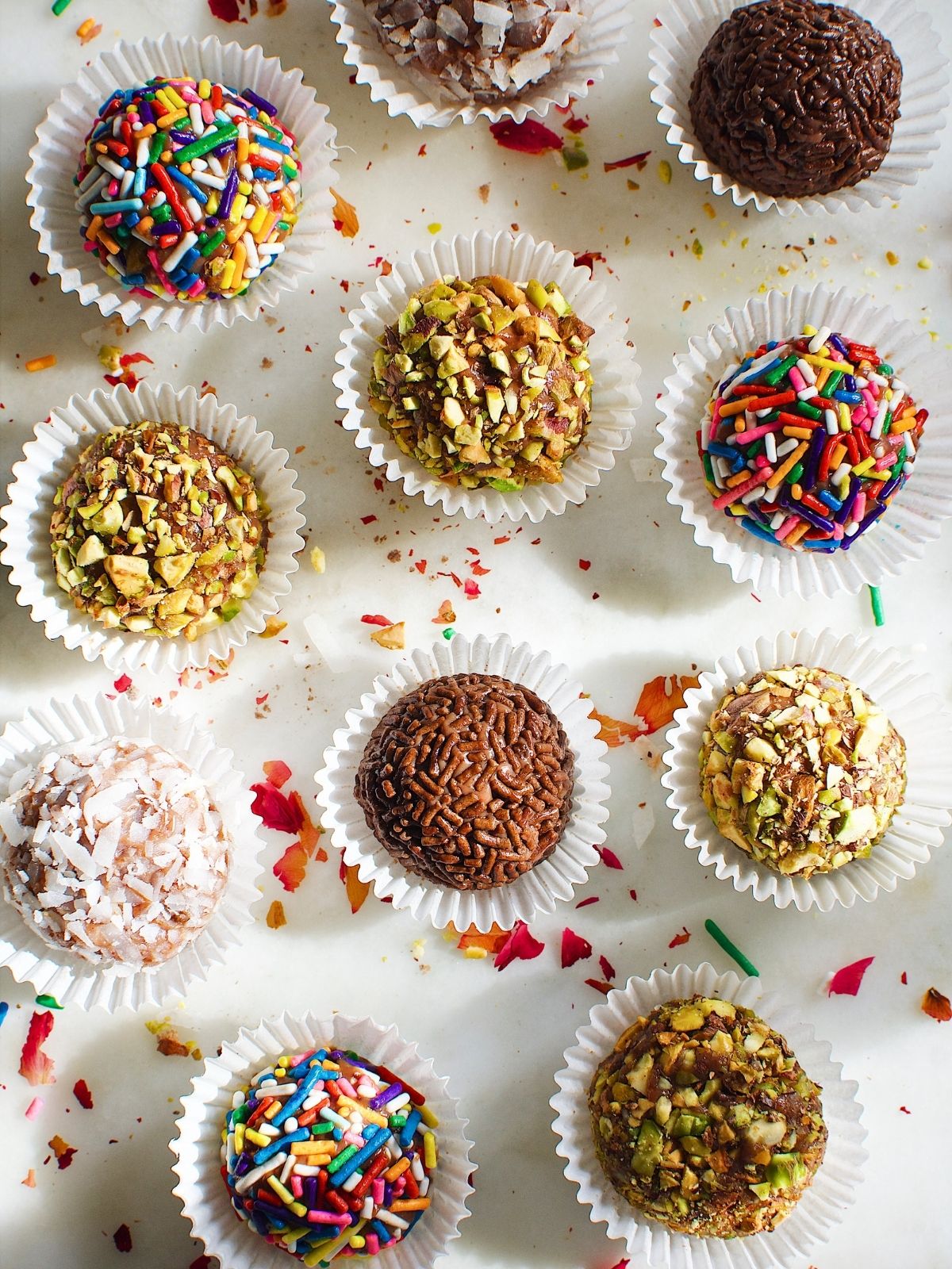brigadeiro balls, coated with chocolate sprinkles, chopped nuts, assorted sprinkles, and coconut flakes, in a mini cupcake liners.