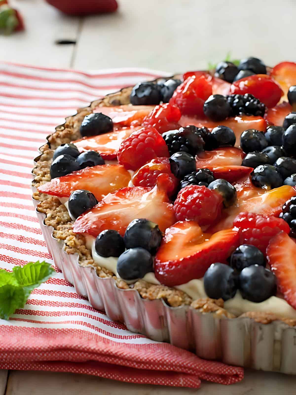 Fruit tart topped with strawberries and berries.