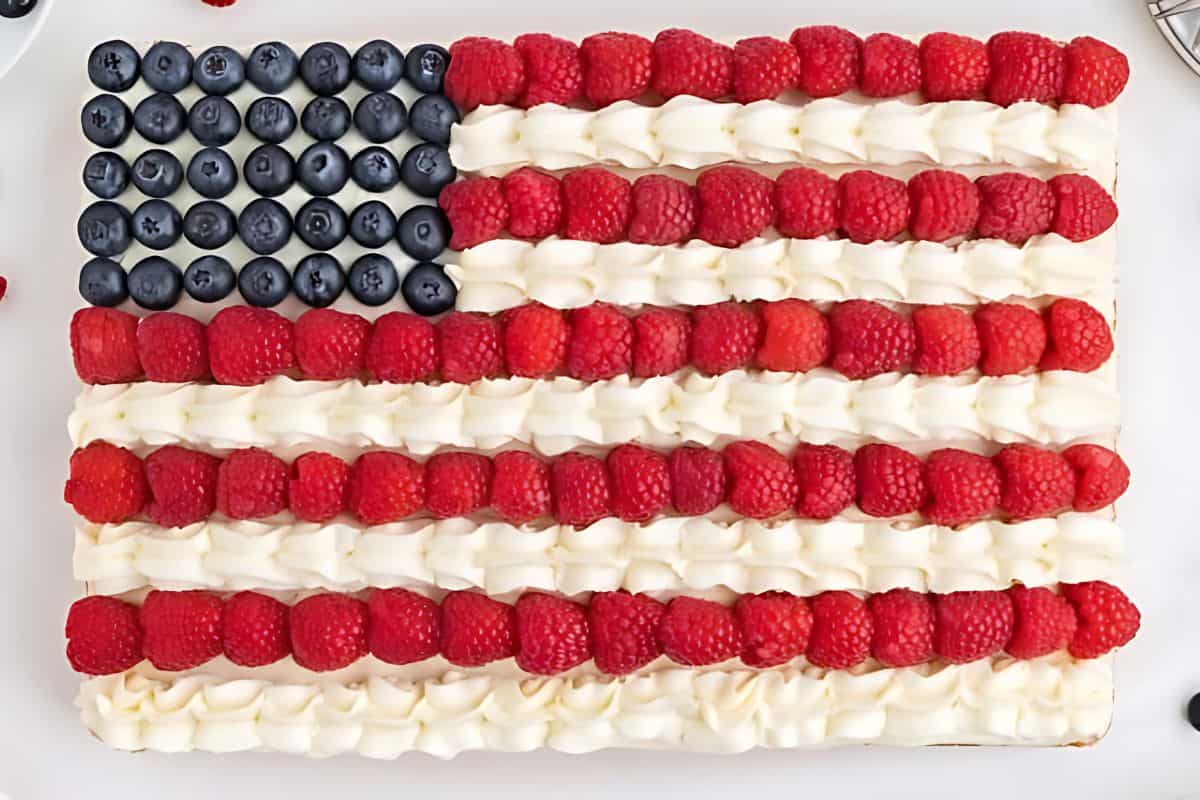 American flag themed independence day cake topped with blueberries and raspberries.