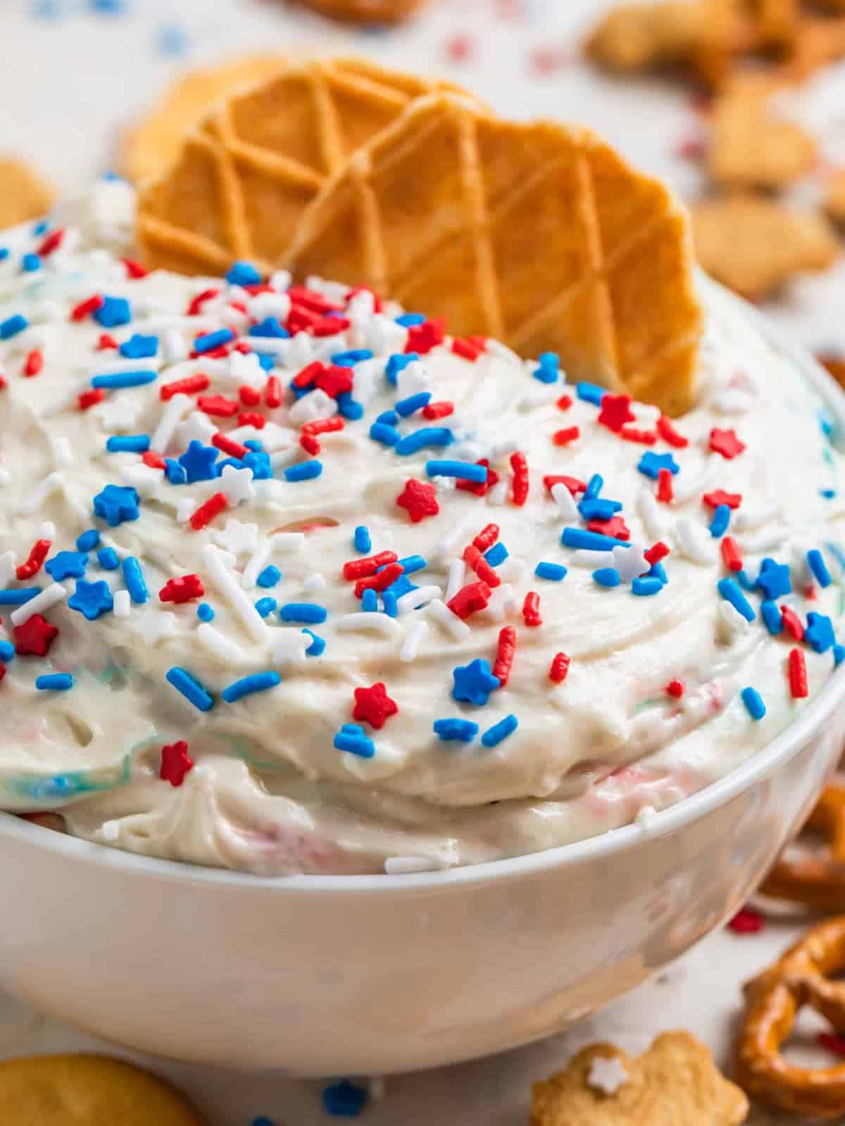 Red white and blue funfetti dip in a bowl with sprinkles on top.