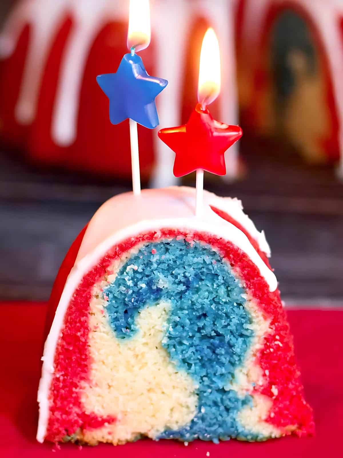 Red white and blue swirl bundt cake with star shaped candles on top.