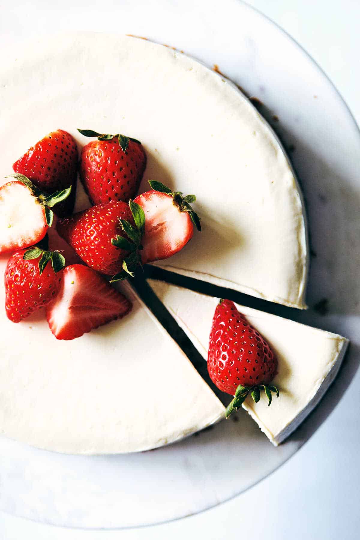Cheesecake with rhubarb sauce topped with strawberries.