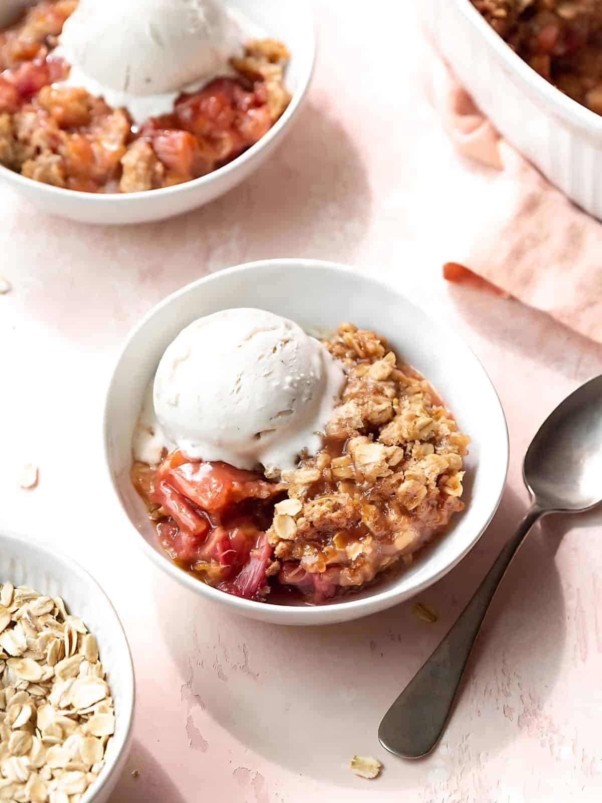 Rhubarb crisps in a bowl topped with ice cream.