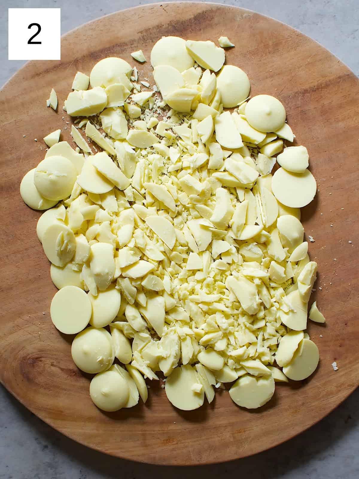 White chocolates being diced on a wooden board.