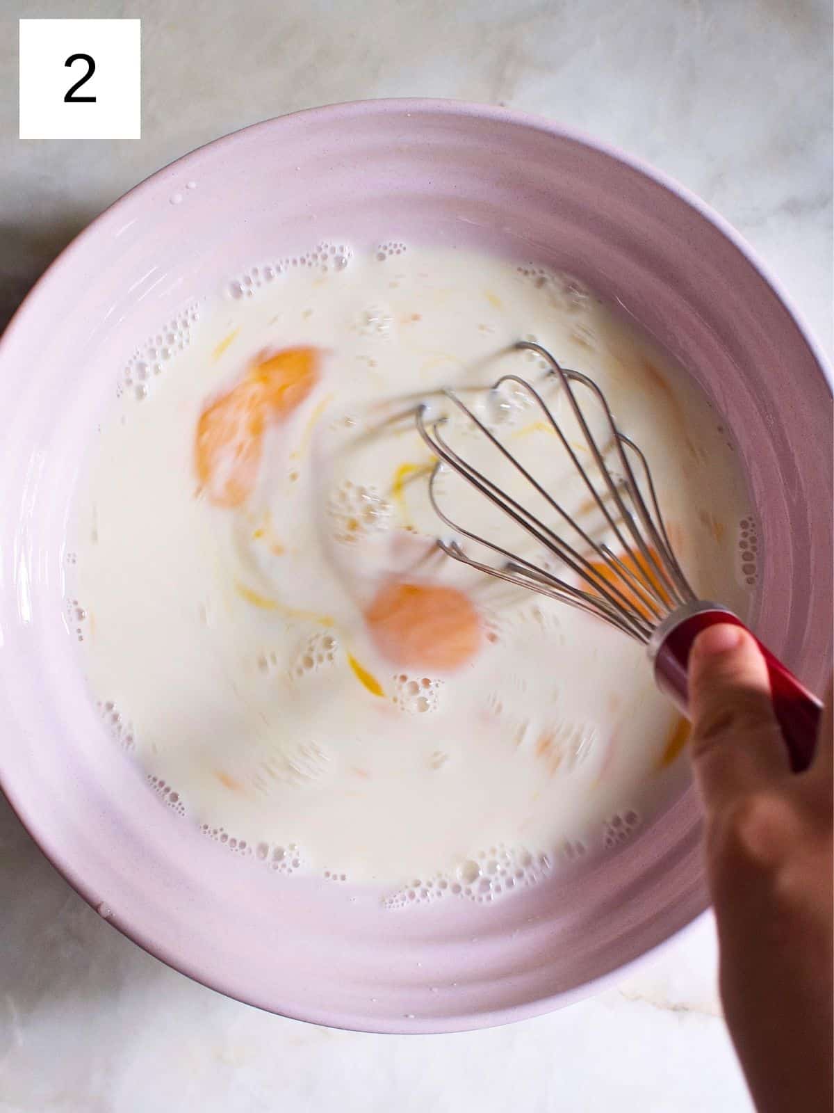 A person whisking a bowl of egg, milk, and maple syrup mixture.