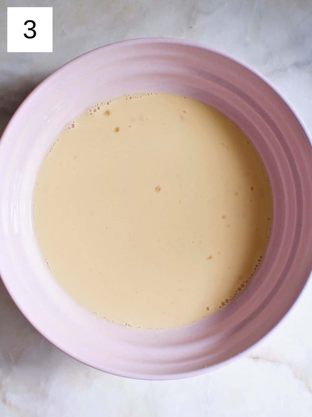 A bowl of whisked eggs, milk, and maple syrup.