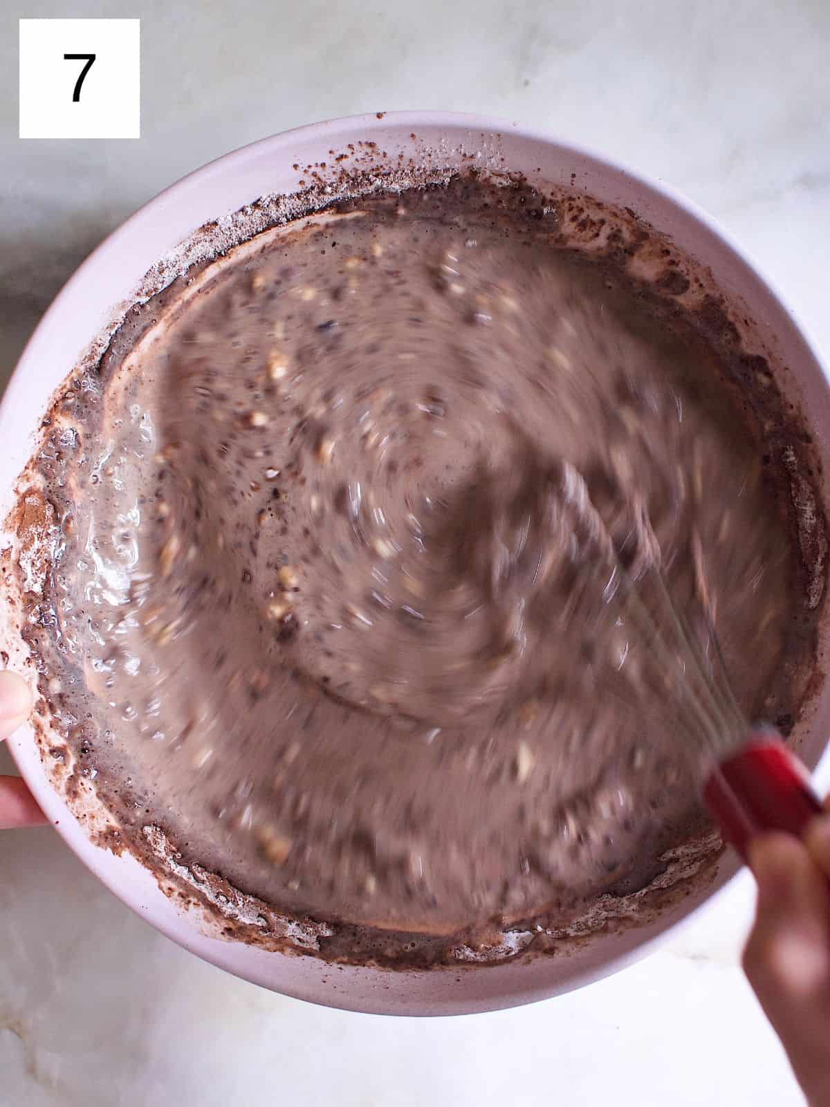 A person whisking a bowl of chocolate crepe batter.