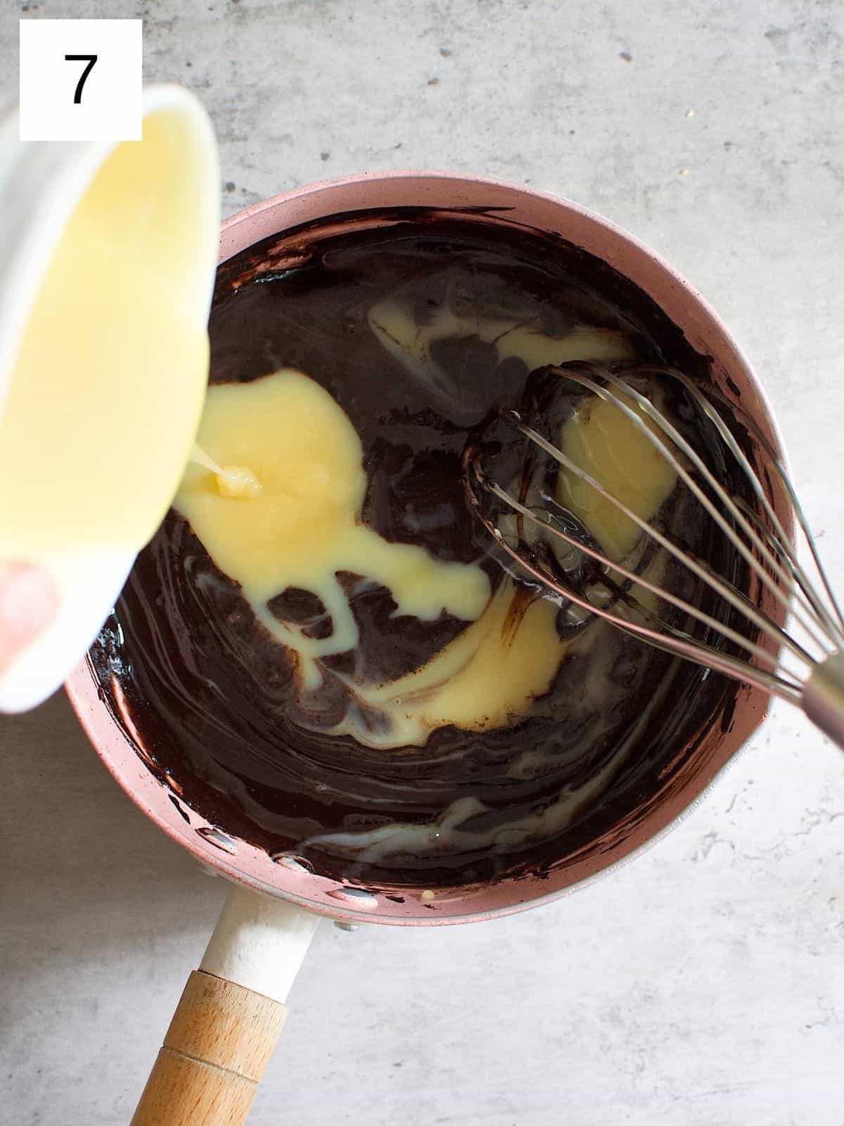 Pouring condensed milk over a bowl of chocolate mixture.