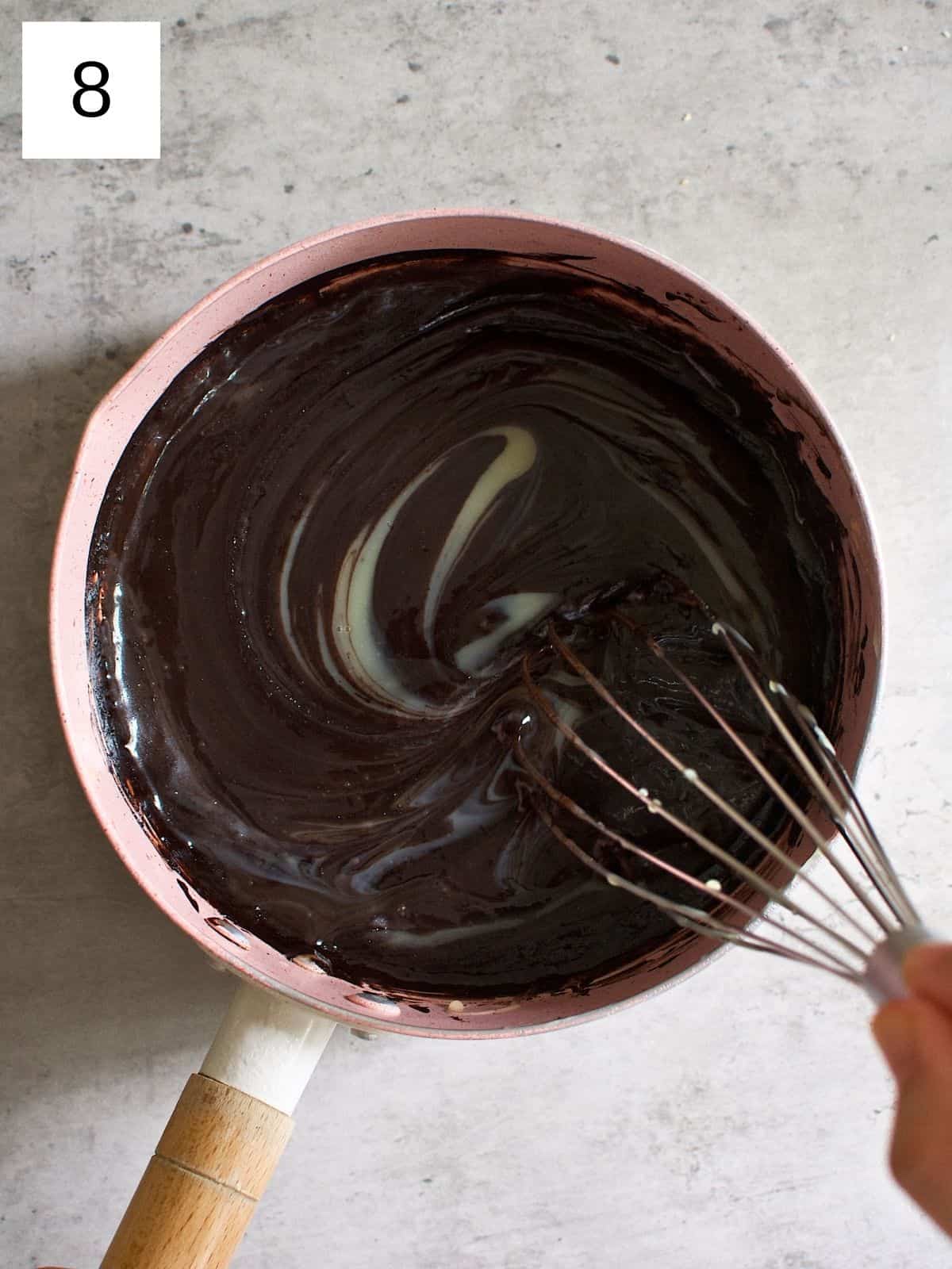 Chocolate mixture with added condensed milk being mixed in a pan.