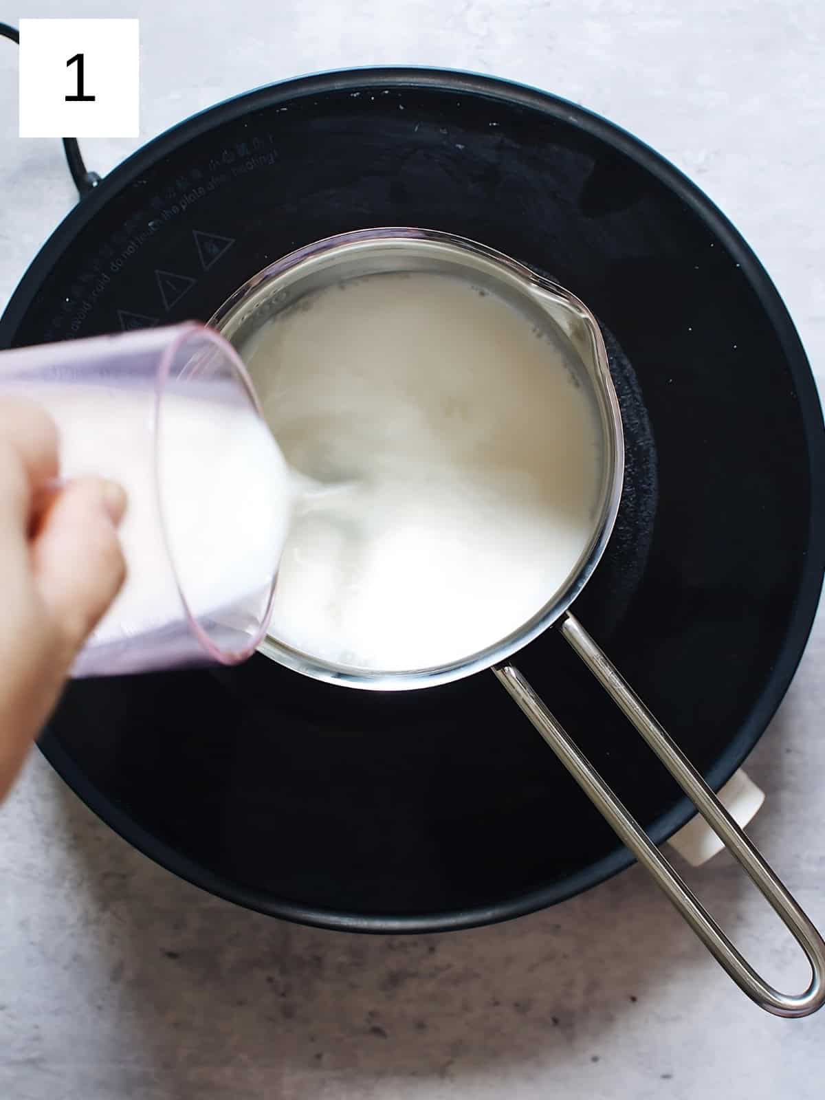 A person pouring milk in a heated pan.