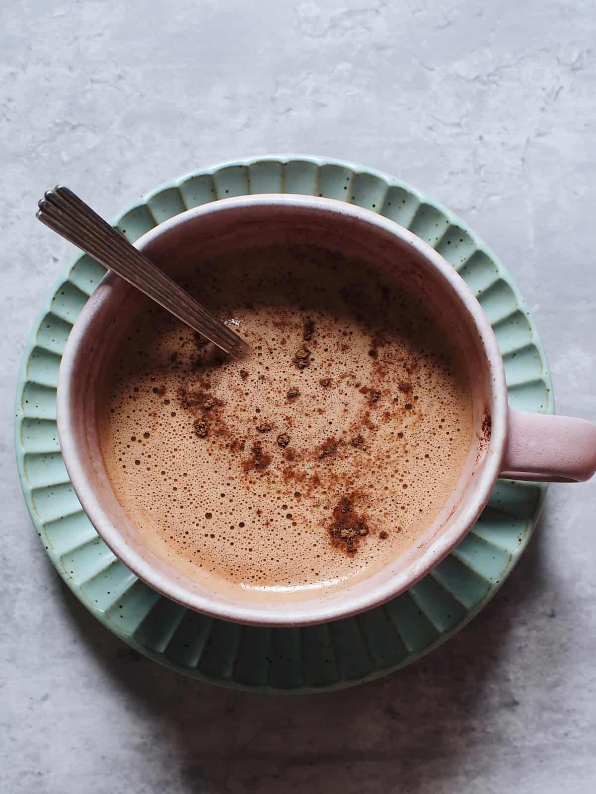 Hot chocolate collagen sprinkled with cinnamon in a cup with a spoon.