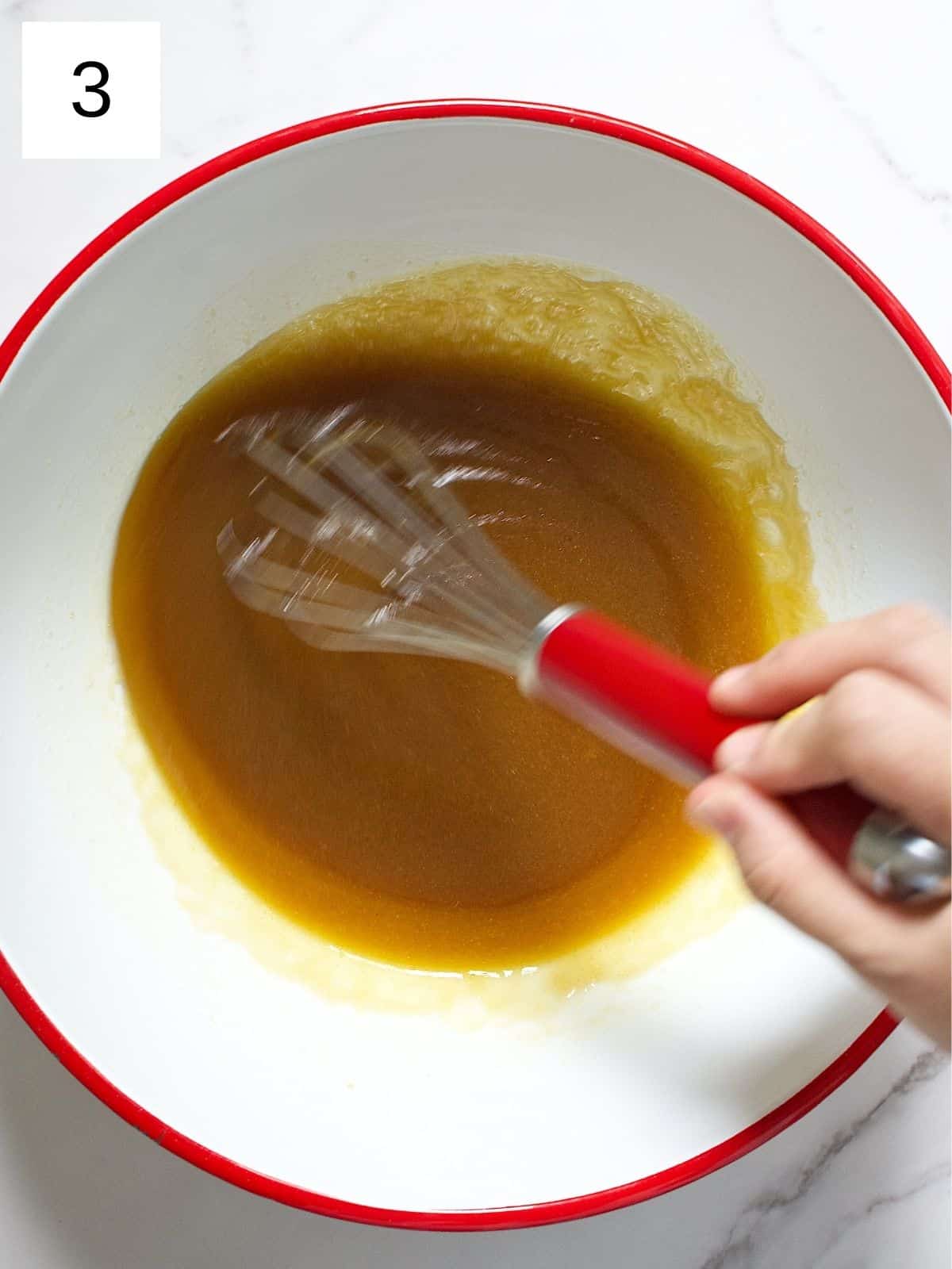 Egg, butter, and brown sugar being whisked in a bowl.