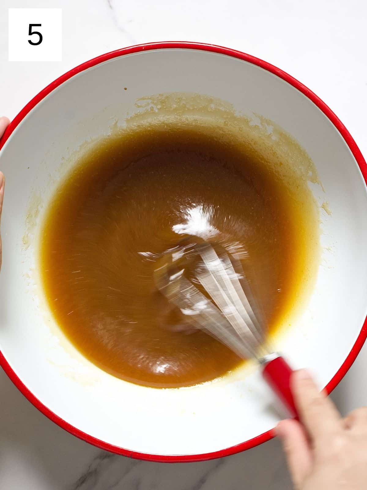 Combined mixture of ingredients being whisked in a bowl.