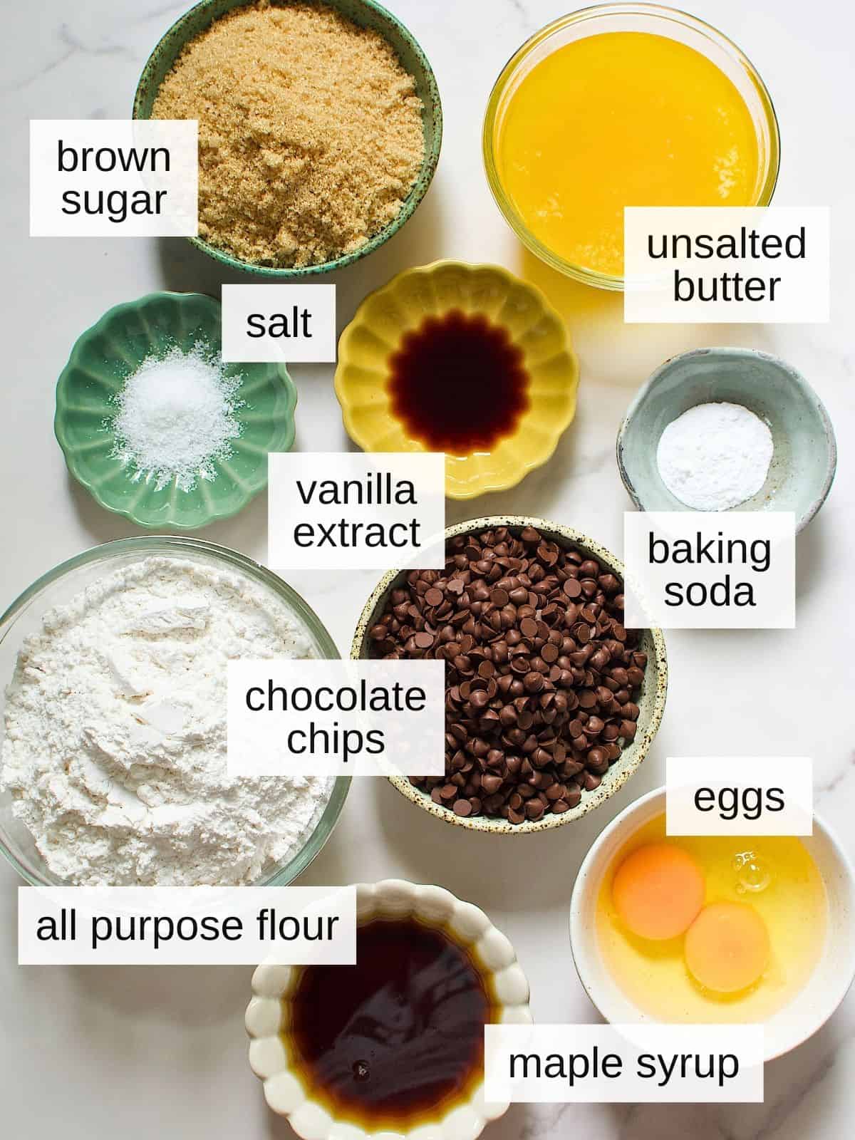 Ingredients for maple syrup chocolate chip cookies: brown sugar, unsalted butter, salt, vanilla extract, baking soda, chocolate chips, flour, eggs, and maple syrup.