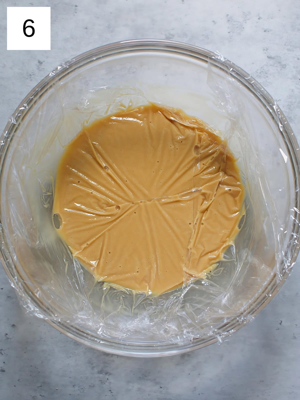 A bowl of chocolate ganache covered with plastic wrap.