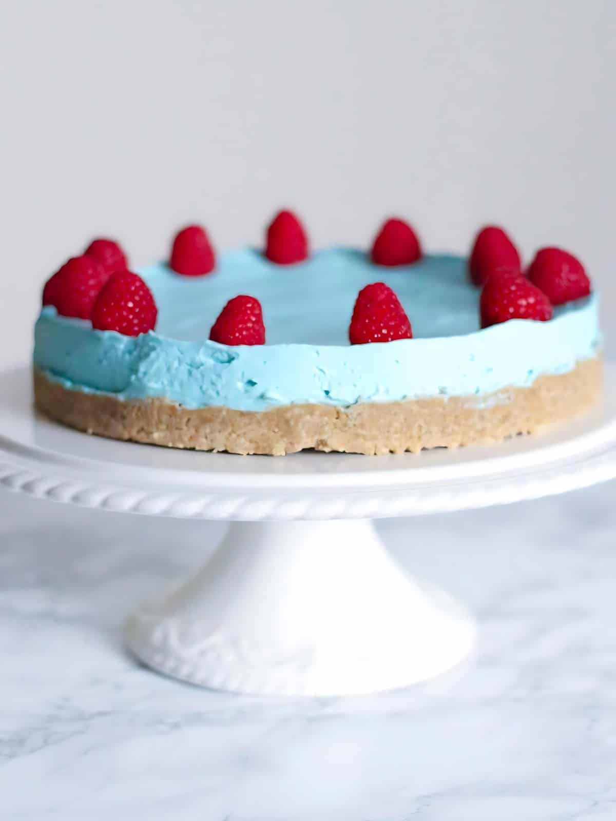 Blue raspberry cheesecake topped with raspberries and blue frosting.