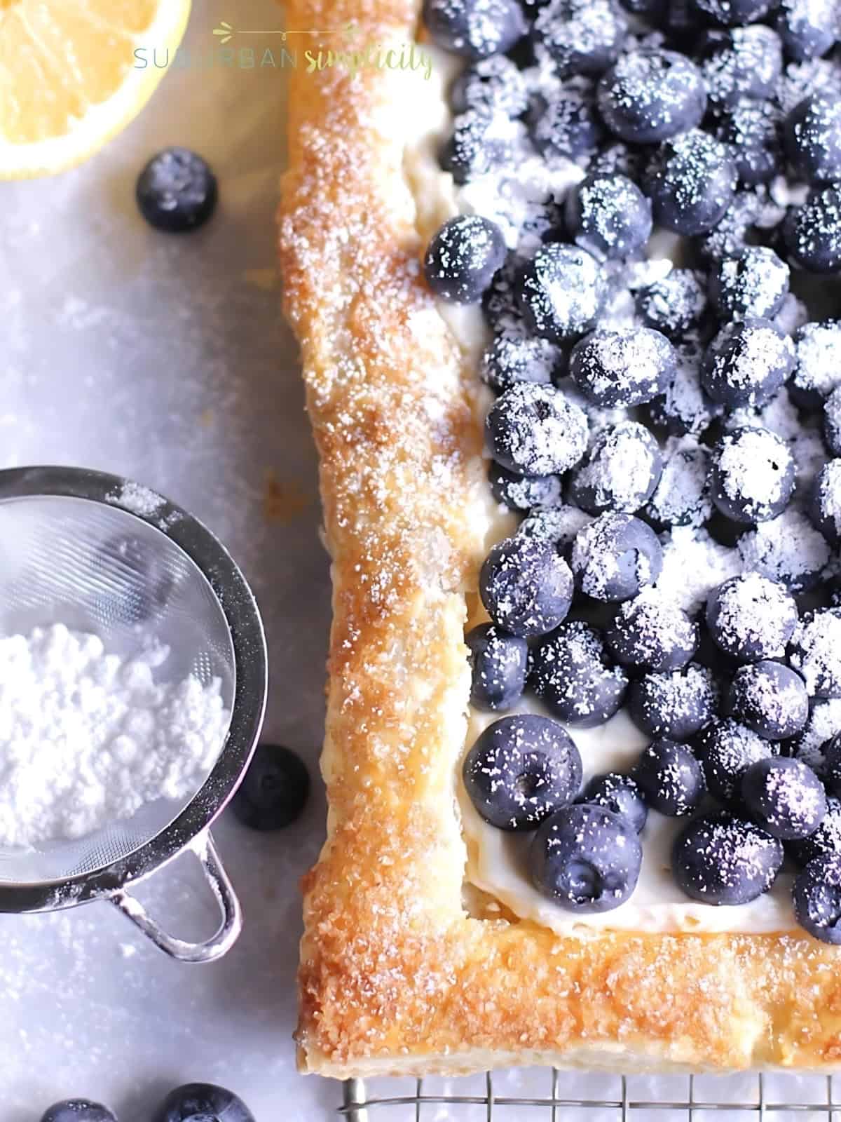 Blueberry puff pastry tarts topped with blueberries and sprinkled with powdered sugar.