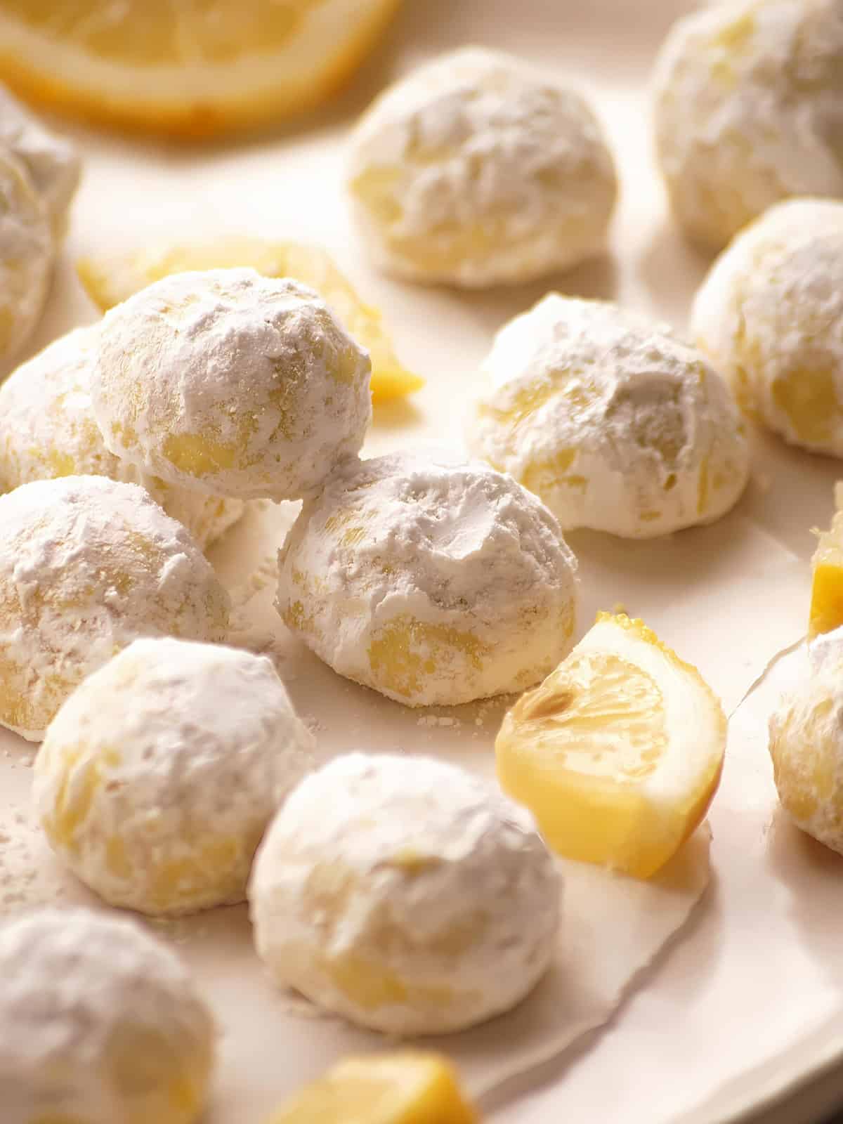 Lemon snowball cookies next to lemon slices.