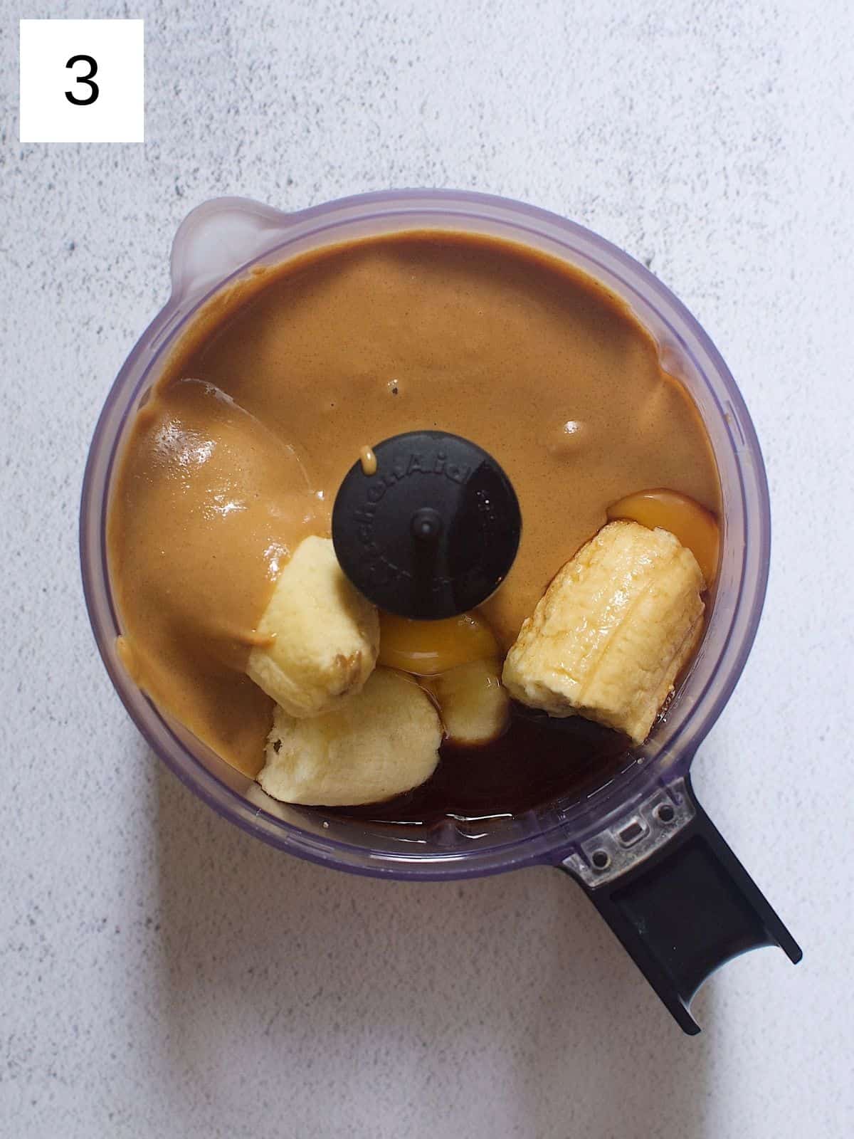 Peeled and sliced bananas placed in a food processor together with nut butter, eggs, and vanilla.