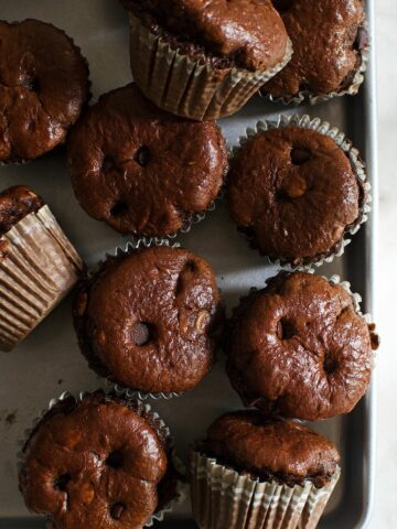 A bunch of banana chocolate protein muffins topped with chocolate chips on a tray.