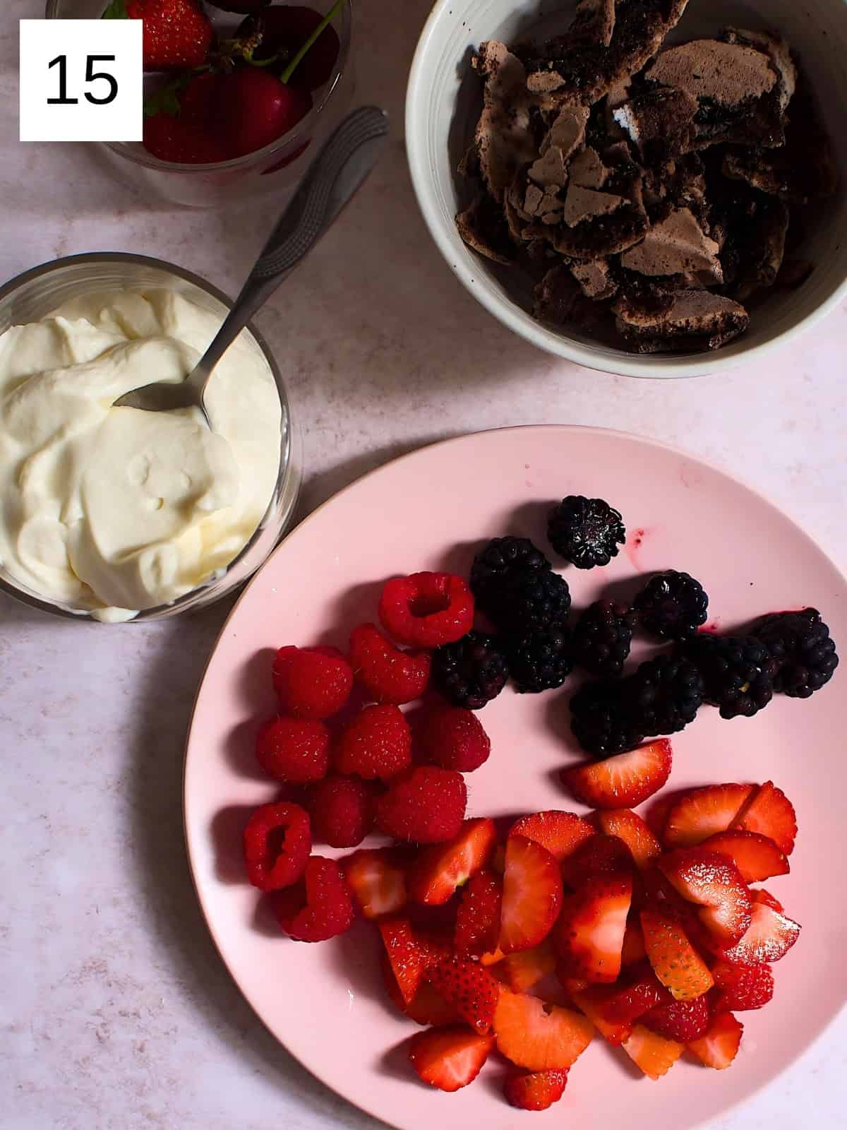 A plate of strawberries, raspberries, and blackberries next to meringue.