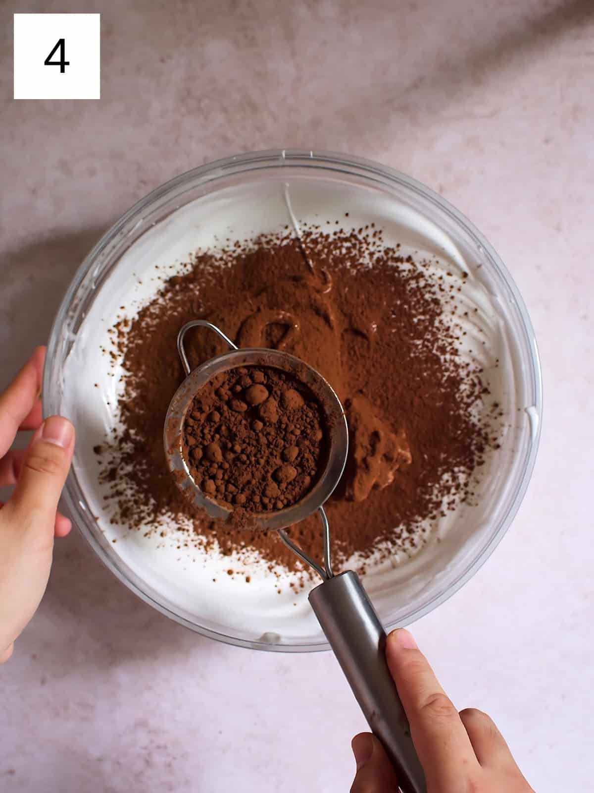 Adding cocoa powder to a bowl of meringue.