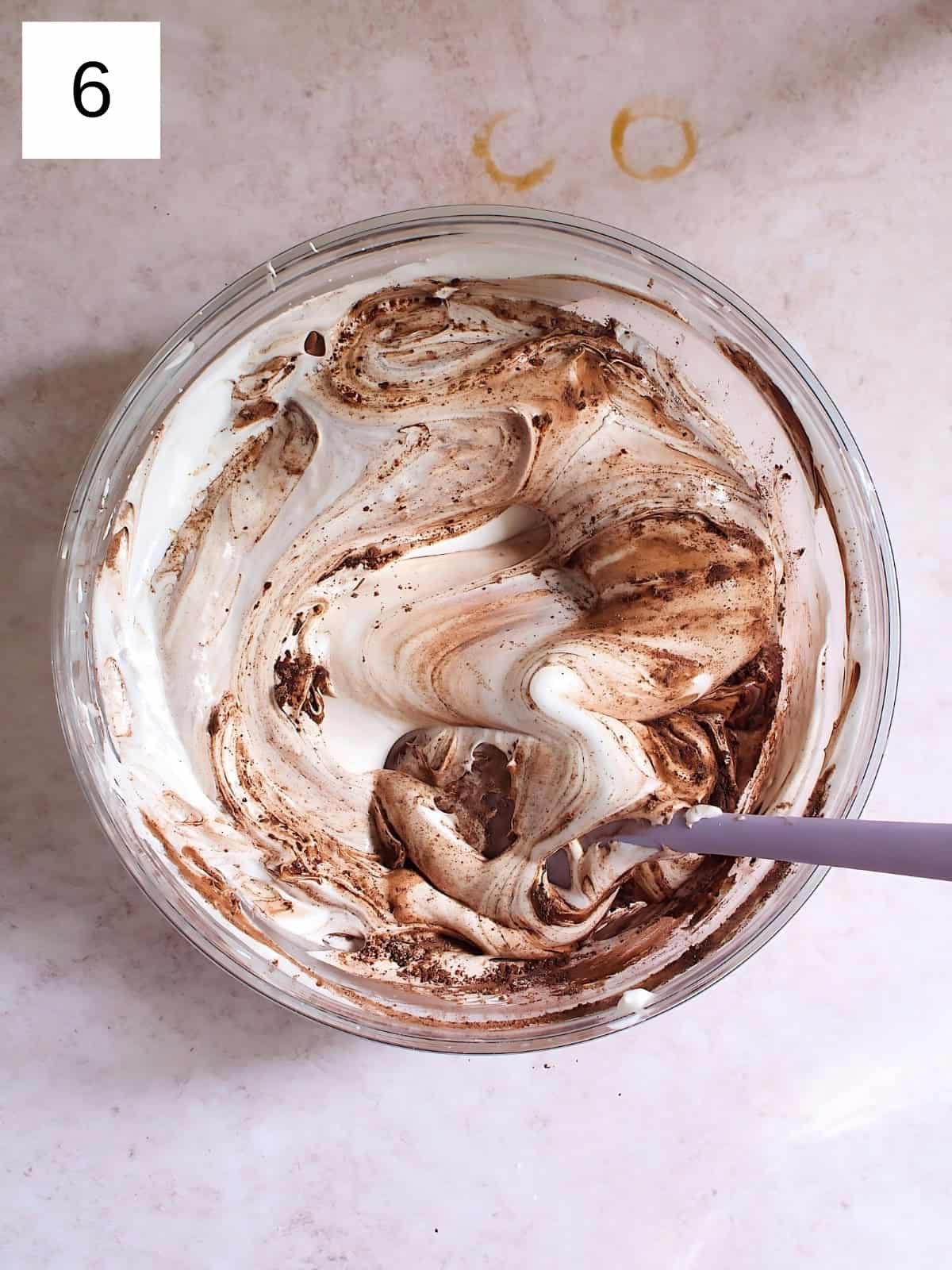 A bowl of meringue with cocoa powder and cream of tartar being mixed.