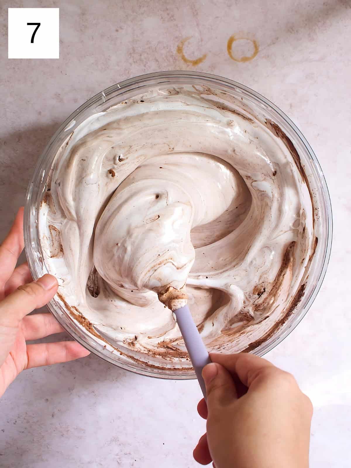 A person continuing to mix a bowl of meringue mixture.