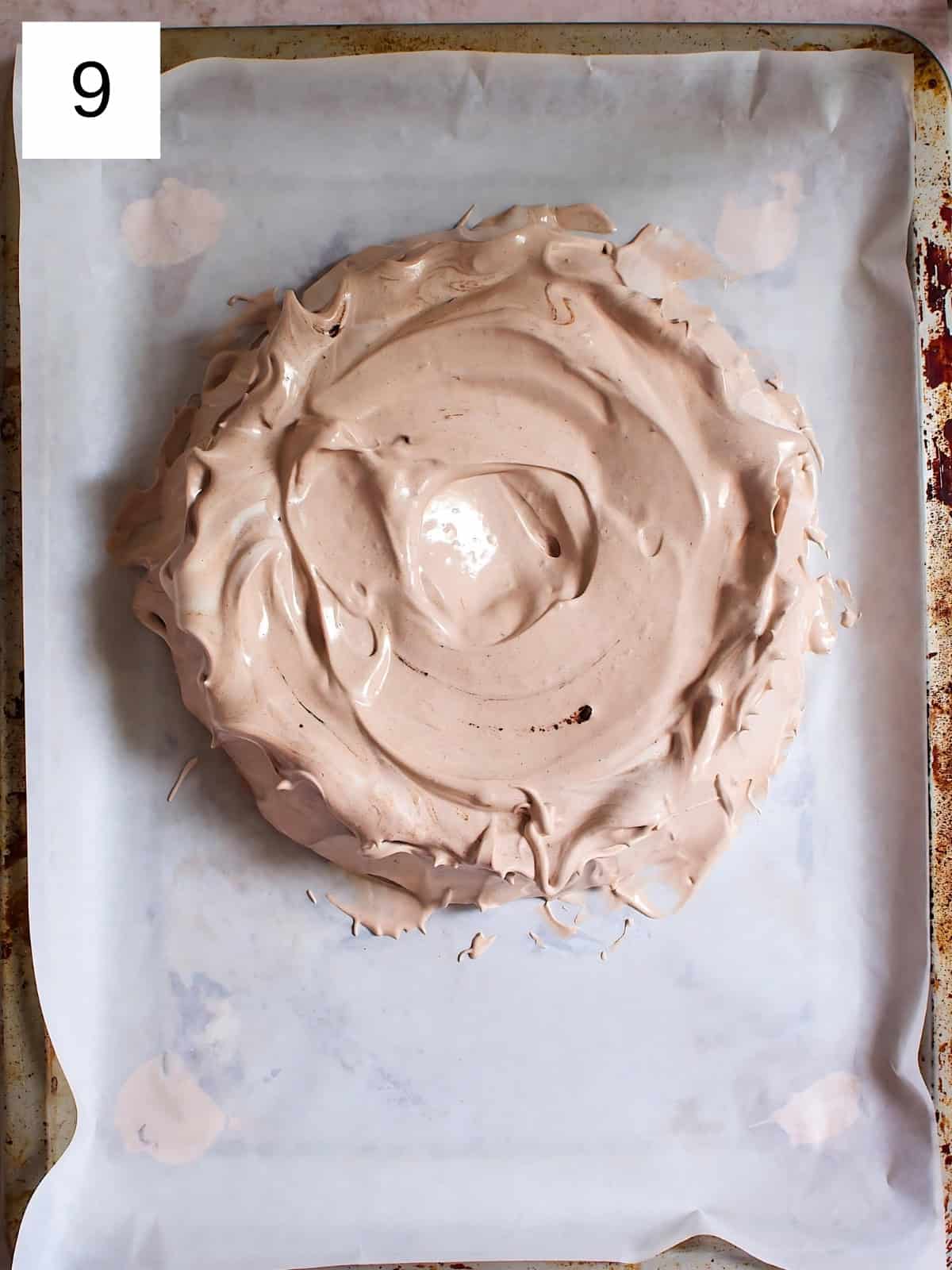 A circular-shaped meringue placed on a baking tray lined with parchment paper.