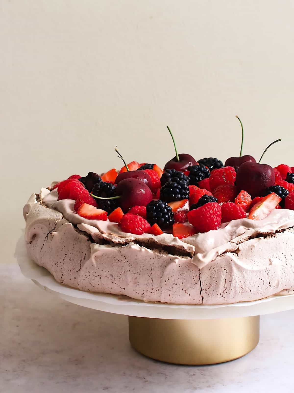 Chocolate pavlova topped with blackberry, cherry, raspberry, and strawberry.